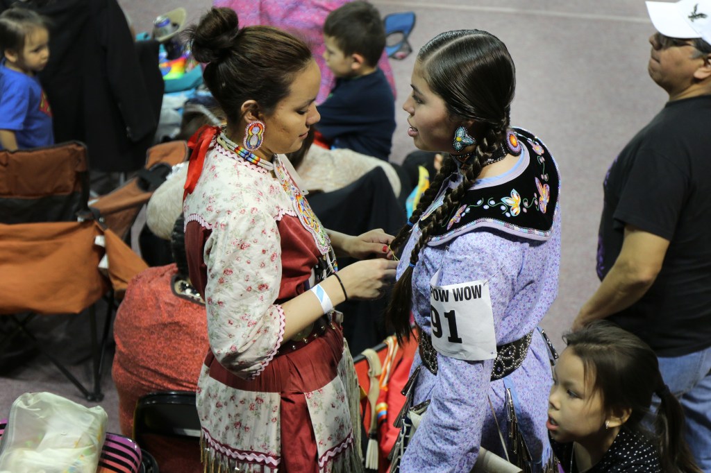 Ayascay Schuyler (left) braids the hair of her niece Maya Schuyler (right) before competing at the 26th Annual Celebrating Life Pow wow in McGuirk Arena on the Campus of Central Michigan University, Saturday, March 21, 2015. 