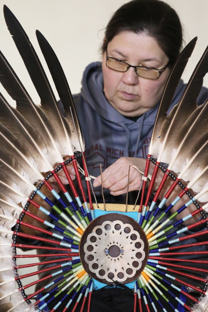 Cid Bearhart prepares her father's Eagle Feathers before competition begins at the 26th Annual Celebrating Life Pow wow in McGuirk Arena on the Campus of Central Michigan University, Saturday, March 21, 2015. 