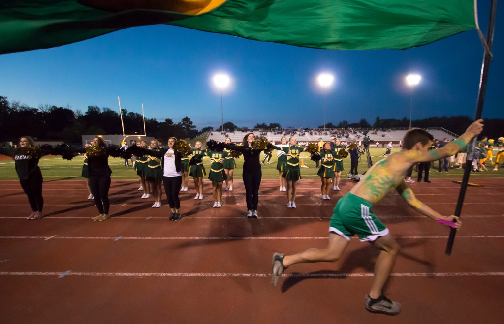 Midland, Michigan native Lauren Rabine, center, performs the charger fight song with the current H. H. Dow Varsity pom pon team and other alumni  during the homecoming game on Sept. 25, 2015. Rabine, who has been pomming consecutively for eight years and graduated from H. H. Dow in 2011, returned to her alma mater this year to be the assistant coach of the varsity team after stepping down from pomming professionally. 