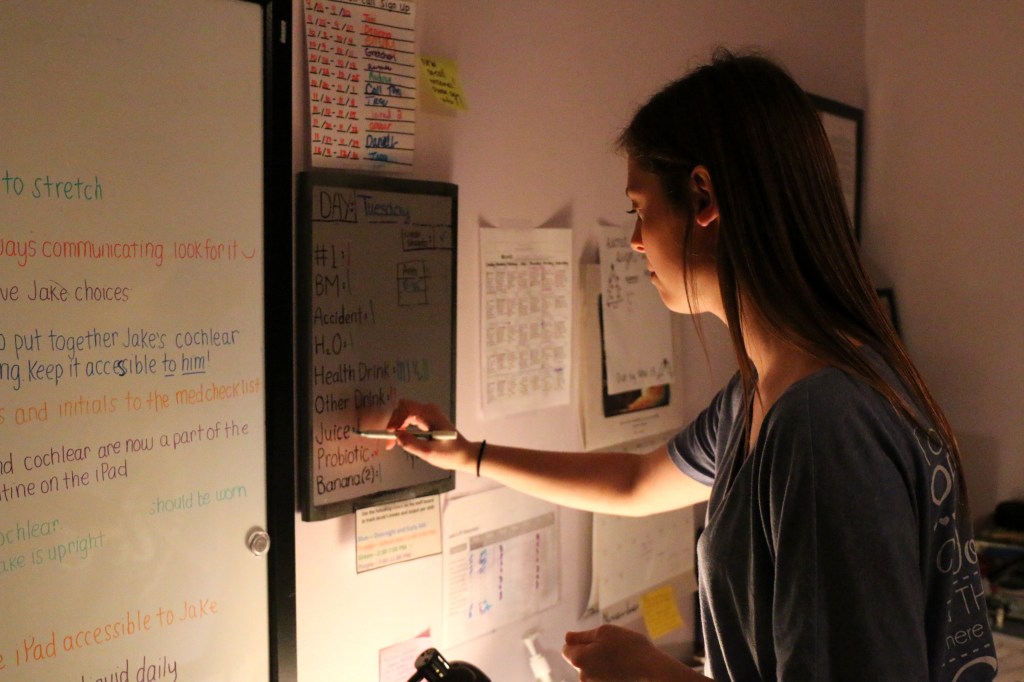 Emily Lane-Waters updates the staff notes in the room dedicated to the twelve care givers that work with Jacob Hartshorne through out the week on Nov. 3, 2015. The caretakers have a room dedicated to them in Jacob's home, so the over night caretaker has a place to sleep.