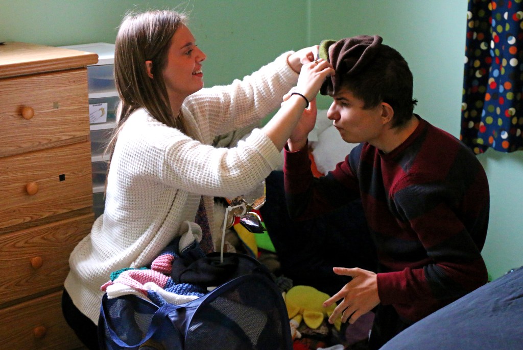 Emily Lane-Waters, a junior at CMU, jokes around with Jacob Hartshorne, a 26-year old man with CHARGE syndrome by playfully placing a hat on his head while cleaning his room on Monday, Oct. 27, 2015.