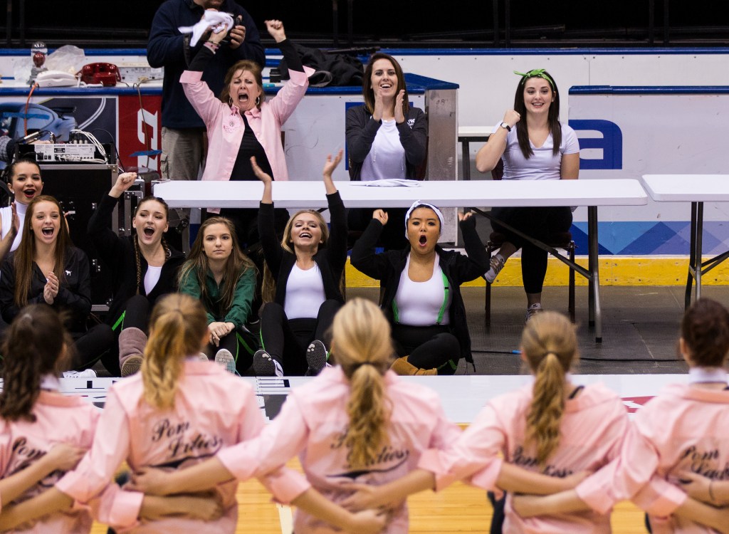 HH Dow JV pom coach Colleen Rabine, left, varsity coach Kerry Robb, center, and assistant varsity coach Lauren Rabine, right, cheer on the HH Dow JV pom team during their performance at the Mid American High Kick Championship Competition on Sunday, Nov. 8, 2015 at the Dow events Center in Saginaw, Michigan. Lauren Rabine has been pomming for 8 years, four of which were with HH Dow.  Her mother, Colleen Rabine has been involved with the HH Dow pom program since Lauren's freshman year. They both now hold a coaching position at the school.